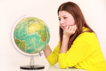 Mädchen schaut sich die Weltkugel an und überlegt