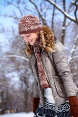 Happy young woman walking in a winter park outdoors