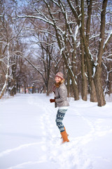 Fototapeta na wymiar Smiling blond girl playing on the snow in a winter park outdoors