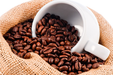 White cup in a bag of coffee beans.