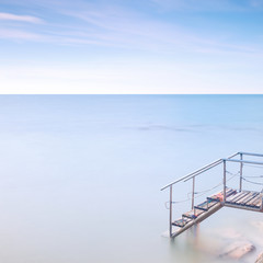 Wooden ladder pier to sea water. Long exposure.