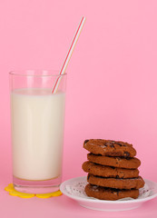 Glass of fresh new milk with cookies on pink background