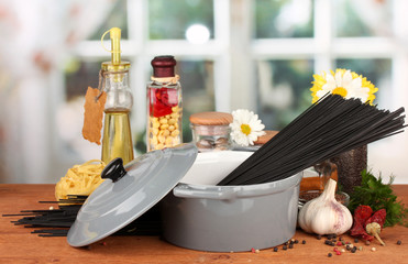 spaghetti in pan on wooden table on bright background