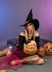 Halloween witch holding pumpkin on color background