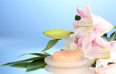 beautiful lily and soap on blue background