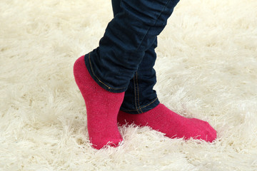 Female legs in colorful socks on  white carpet background