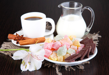 Cup of coffee with rahat delight and milk on wooden table