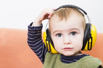 young child on couch with earmuffs