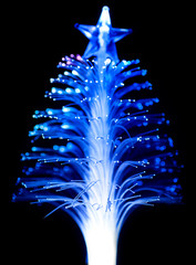 Blue fiber optic Christmas tree light on black background.