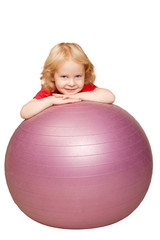 blond baby with blue eyes smiling and playing with fitness ball