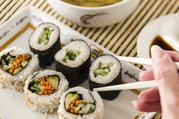Picking up vegetable sushi with chop sticks