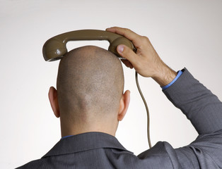 Ejecutivo sujetando un auricular sobre su cabeza, de espaldas.
