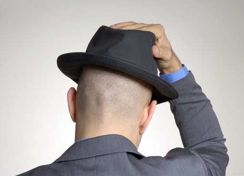 Vista trasera de un hombre coloc&aacute;ndose un sombrero.