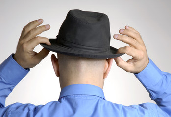 Vista trasera de un hombre colocándose un sombrero.