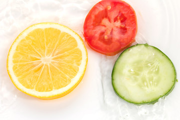 lemon cucumber and tomato in the water on a white background