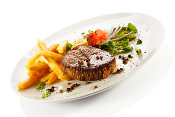 Grilled steaks, French fries and vegetables