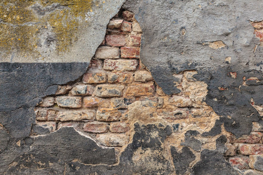 Old damaged wall with bricks and stucco