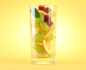 transparent glass with citrus fruits, on yellow background