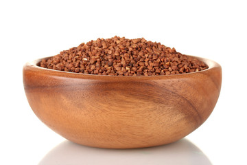 Raw buckwheat in wooden bowl isolated on white