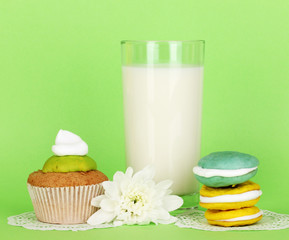 Glass of fresh new milk with cakes on green background