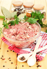 Bowl of raw ground meat with spices on wooden table