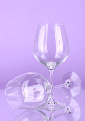 Two empty wine glasses on color background
