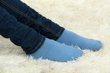 Female legs in colorful socks on  white carpet background