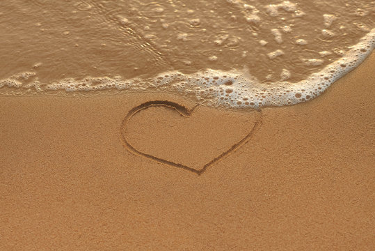 Heart drawing in the sand on the morning beach