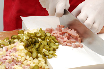 Manos cortando vegetales y carne,cocinando receta.