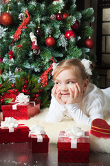 Obraz na płótnie Canvas Happy girl with giftslying near christmas tree