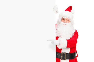 Santa claus posing next to a blank billboard and pointing