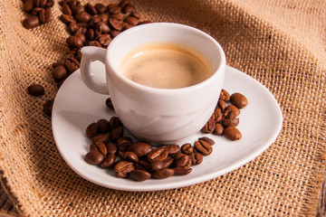 Cup of italian espresso on jute background and coffee beans