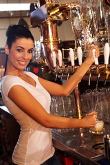 Female bartender tapping draught beer in pub