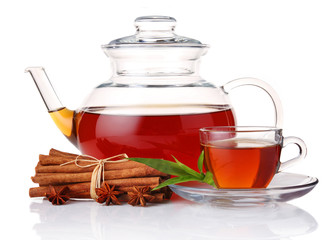 Teapot and cup of tea with green leaves and cinnamon sticks