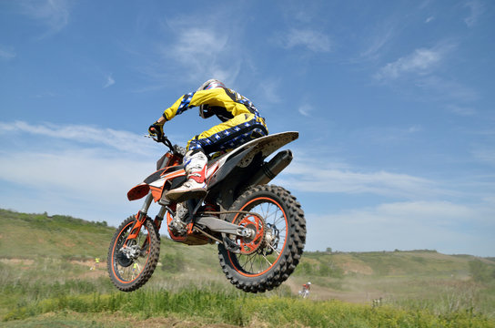 Driver motorcycle MX flies over hill