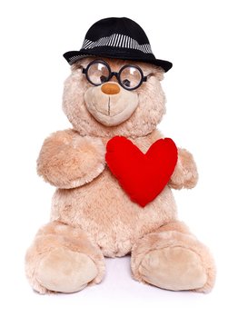 Teddy bear wearing hat holds red heart