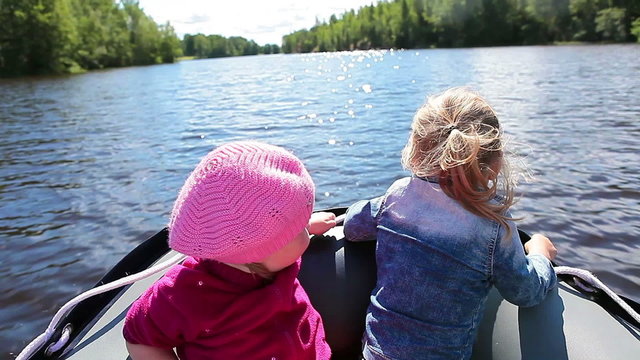 Two little girls on motorboat stern during movement