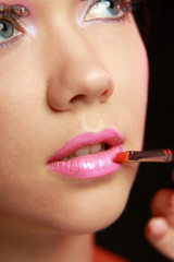 A beautiful young woman doing make-up, isolated on white