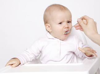 jedzące niemowlę w krzesełku na białym tle - obrazy, fototapety, plakaty