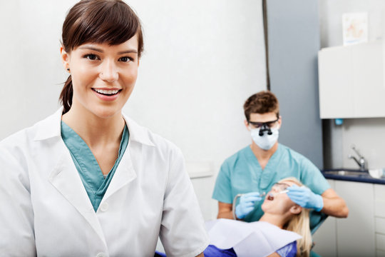 Female Assistant With Dentist Working In The Background