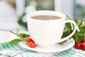 cup of tea with hip roses, on wooden table