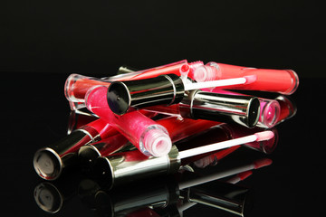 beautiful lip glosses with rose petals, on black background