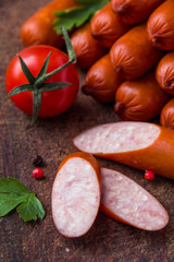 Sausages on wooden board with cherry tomato
