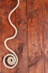 Frame composed of rope on wooden background