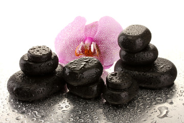 Spa stones and orchid flower, on wet background.