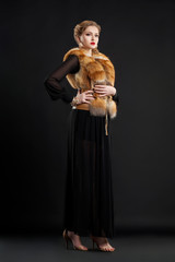 Fototapeta premium Fashion Model in Fur Collar and Black Dress Posing in Studio