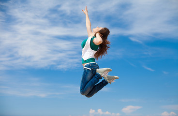 sporty woman jumping against the clear blue sky on beach