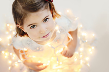 Cute, smiling little girl with glowing Christmas lights