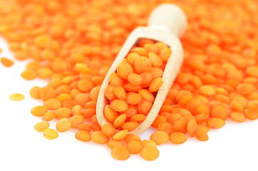Red lentils poured from wooden spoon