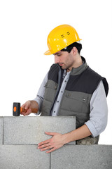 Mason using mallet to knock building blocks into place